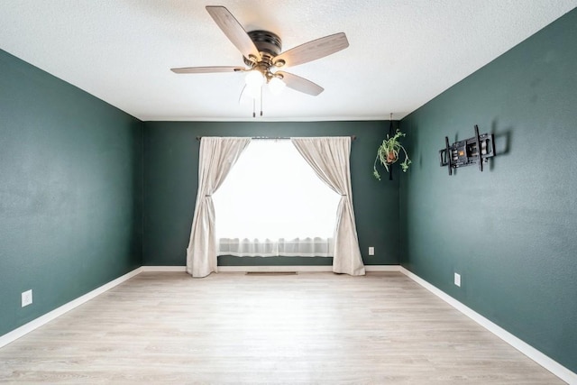 spare room with ceiling fan, a textured ceiling, and light wood-type flooring