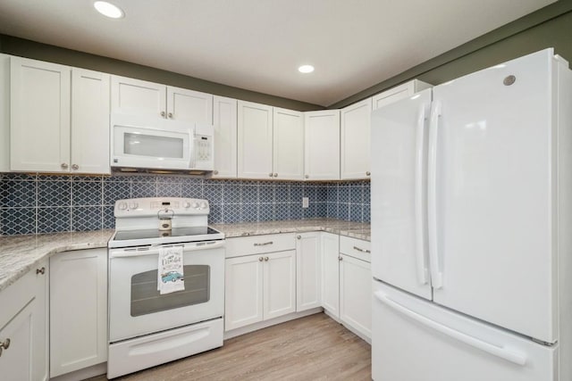 kitchen with white appliances, white cabinetry, backsplash, light stone counters, and light hardwood / wood-style floors