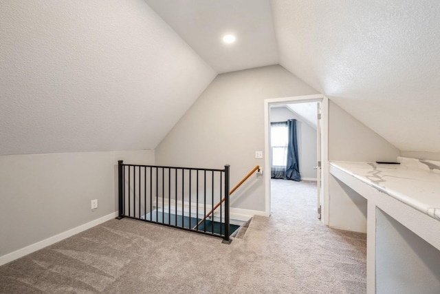 additional living space featuring light colored carpet, lofted ceiling, and a textured ceiling