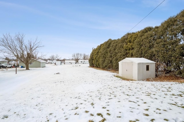 yard layered in snow featuring a storage shed