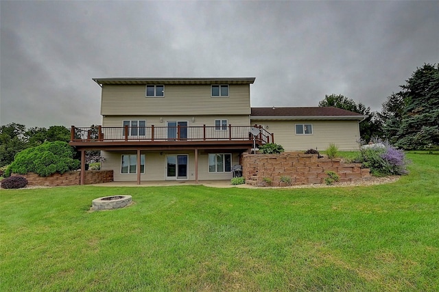 back of property with a wooden deck, a fire pit, a patio area, and a lawn