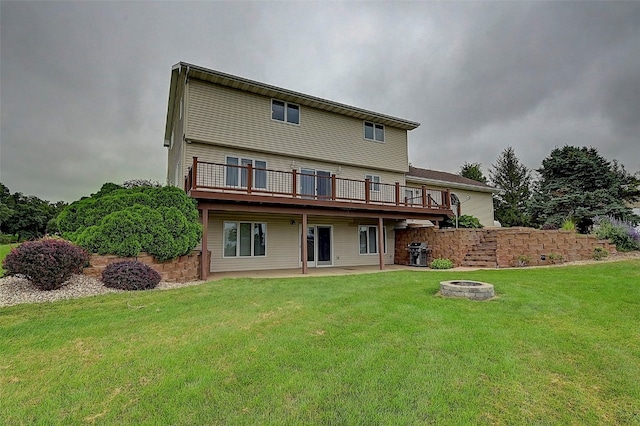 rear view of house featuring a deck, a lawn, a patio area, and a fire pit