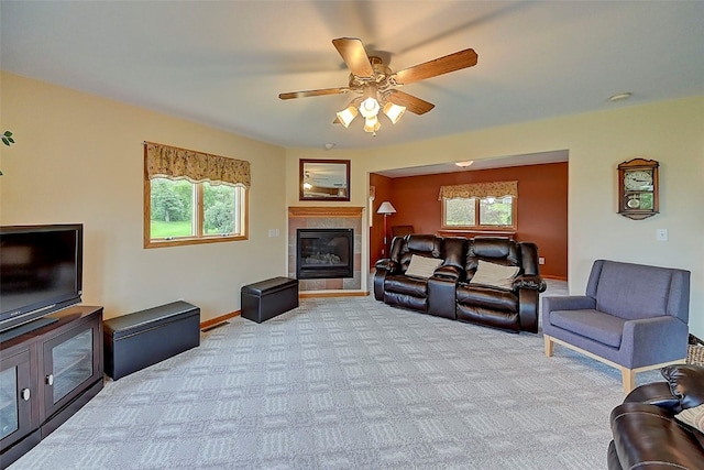 carpeted living room with a tiled fireplace and ceiling fan