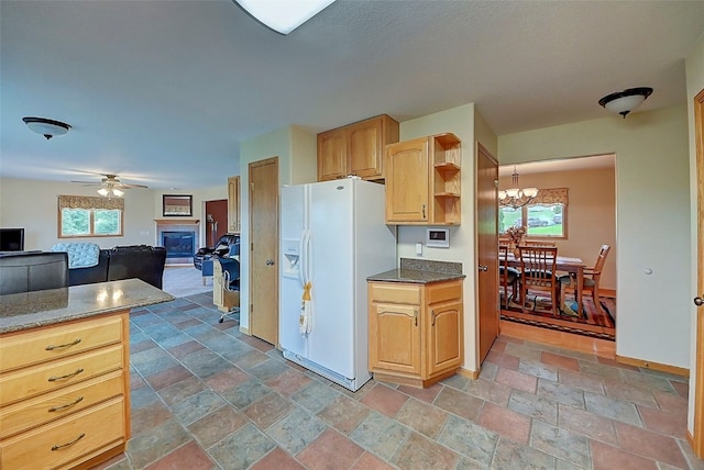 kitchen featuring ceiling fan with notable chandelier, white fridge with ice dispenser, a wealth of natural light, and light brown cabinetry