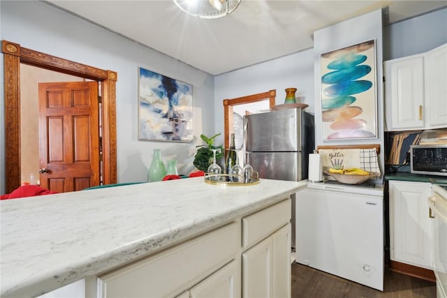 kitchen featuring light stone countertops, dark hardwood / wood-style flooring, refrigerator, white cabinets, and stainless steel refrigerator