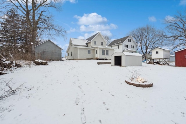 snow covered house featuring a storage shed