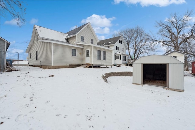 snow covered back of property with a storage unit