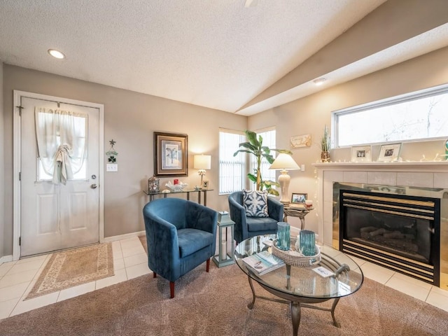 interior space with baseboards, a tile fireplace, vaulted ceiling, a textured ceiling, and recessed lighting