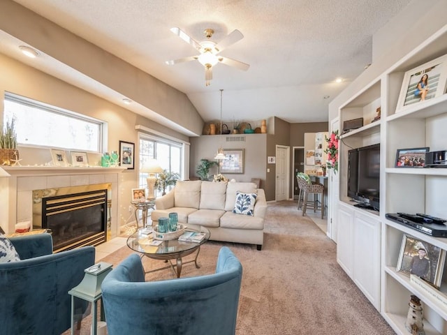 living area with a textured ceiling, light carpet, a ceiling fan, vaulted ceiling, and a tiled fireplace