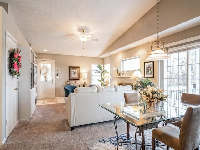 dining area featuring lofted ceiling, a textured ceiling, plenty of natural light, and light colored carpet