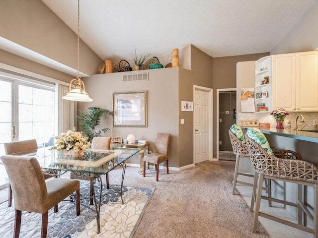 dining room with light carpet, high vaulted ceiling, baseboards, and visible vents