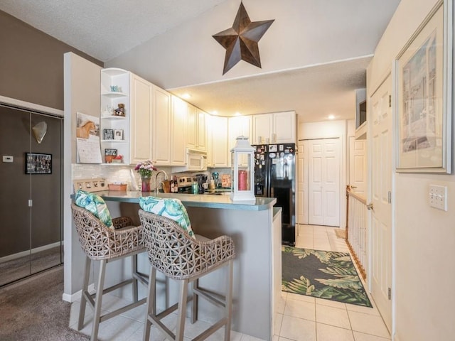 kitchen with white microwave, light tile patterned flooring, a peninsula, open shelves, and a kitchen bar