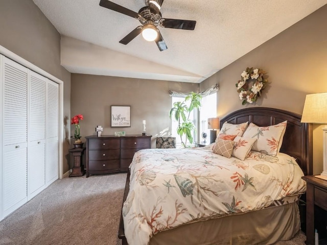 carpeted bedroom featuring a ceiling fan, lofted ceiling, a closet, and a textured ceiling