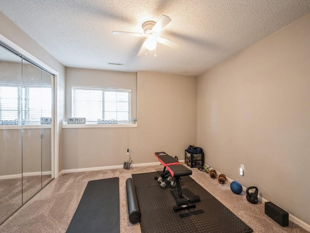 workout area with a textured ceiling, carpet floors, a ceiling fan, and baseboards