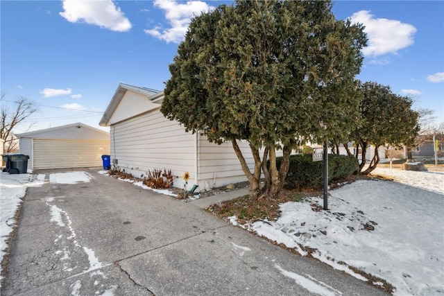 view of snowy exterior with a garage and an outdoor structure