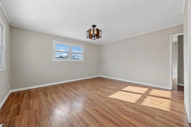 unfurnished room featuring hardwood / wood-style floors, crown molding, and a chandelier