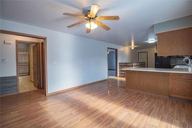 kitchen with ceiling fan, light hardwood / wood-style floors, kitchen peninsula, and sink