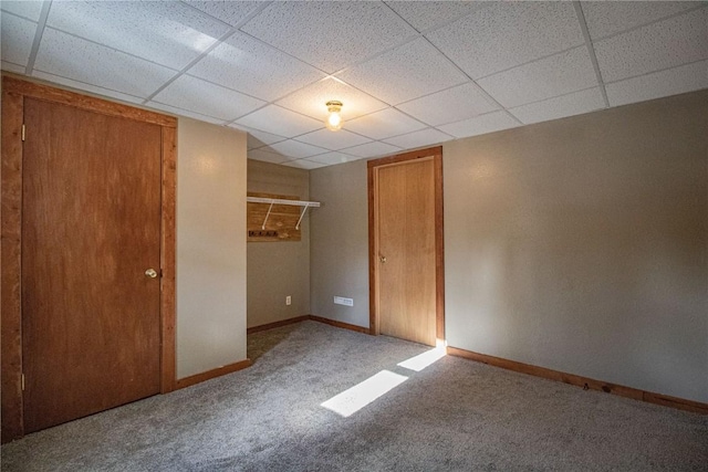 unfurnished bedroom with carpet flooring, a drop ceiling, and a closet