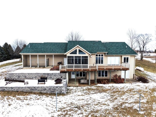 snow covered rear of property with a deck