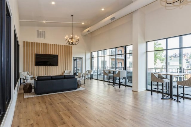 living room with a chandelier, light wood-type flooring, a healthy amount of sunlight, and visible vents