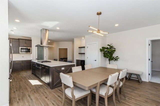 dining space featuring recessed lighting, a notable chandelier, baseboards, and wood finished floors