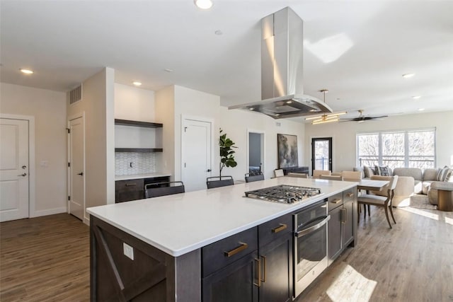 kitchen featuring light countertops, appliances with stainless steel finishes, a kitchen island, and island exhaust hood