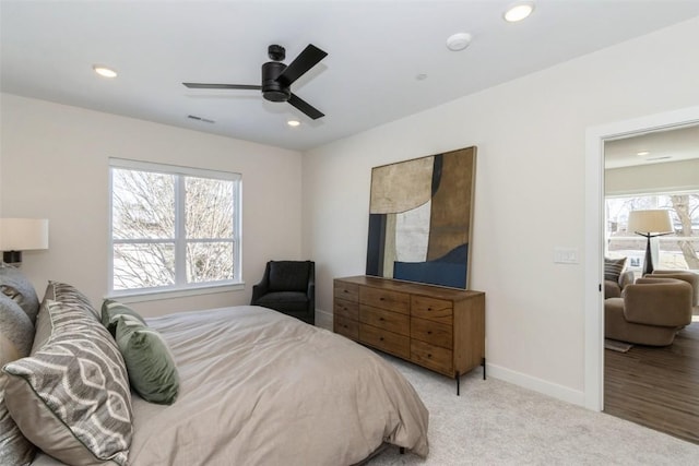 bedroom featuring multiple windows, recessed lighting, light colored carpet, and baseboards