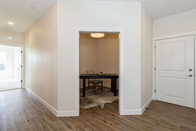 hall featuring dark wood finished floors, visible vents, and baseboards