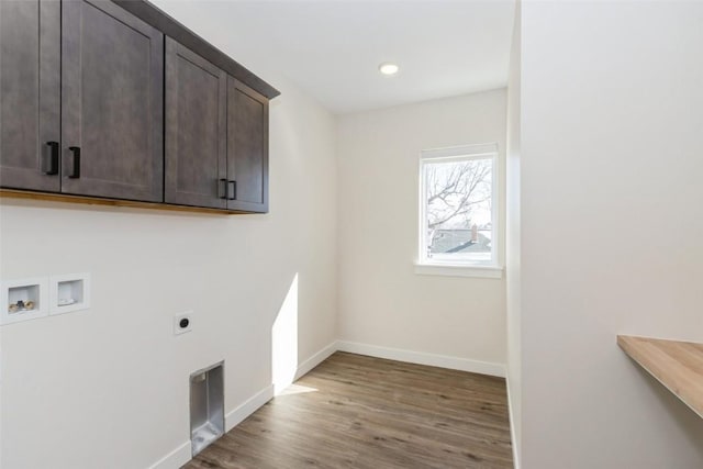 laundry room featuring dark wood-style floors, cabinet space, electric dryer hookup, and baseboards