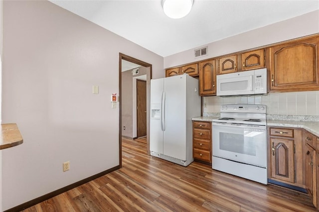 kitchen with brown cabinetry, white appliances, and visible vents