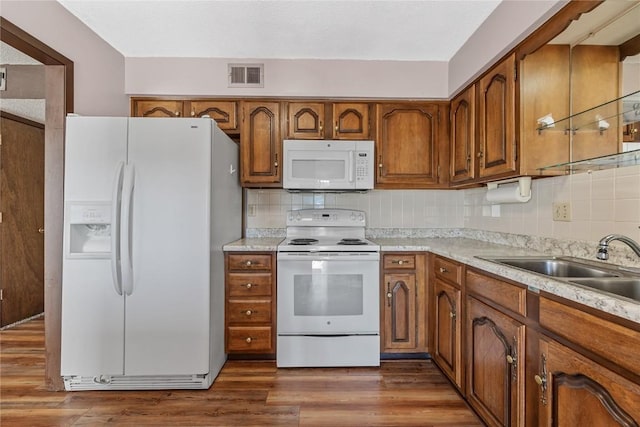 kitchen with white appliances, dark wood-type flooring, visible vents, brown cabinets, and decorative backsplash