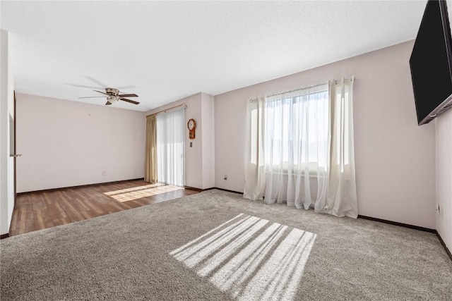 unfurnished living room with a textured ceiling, carpet, a ceiling fan, and baseboards