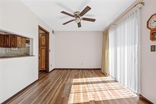 spare room with a ceiling fan, baseboards, and wood finished floors