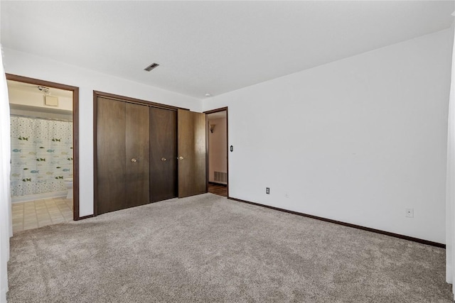 unfurnished bedroom with ensuite bathroom, carpet flooring, visible vents, baseboards, and a closet