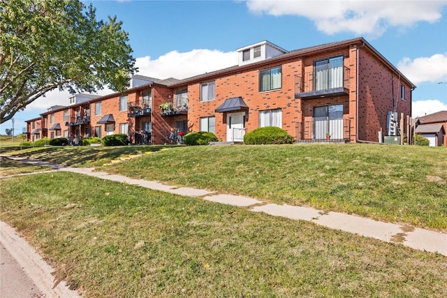 multi unit property featuring a front yard and brick siding