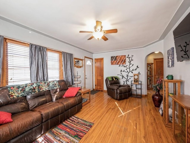 living area with arched walkways, ceiling fan, and wood finished floors