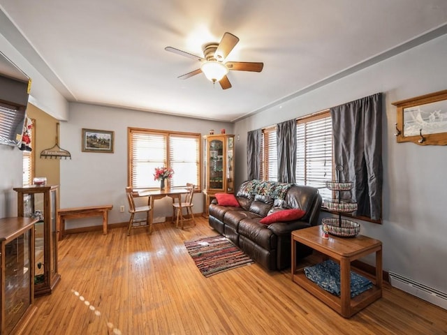 living area featuring ceiling fan, light wood-type flooring, a baseboard radiator, and a wealth of natural light