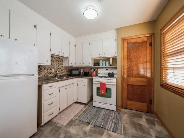 kitchen featuring white appliances, white cabinets, dark countertops, a sink, and backsplash