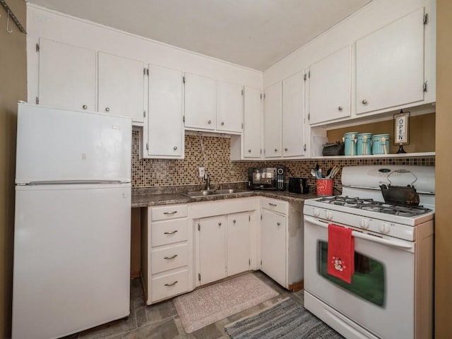 kitchen featuring tasteful backsplash, dark countertops, white cabinets, a sink, and white appliances