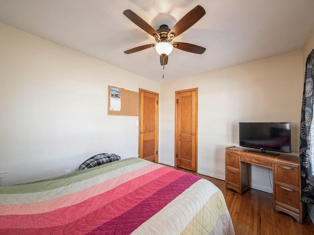 bedroom featuring dark wood-style floors, a ceiling fan, and baseboards