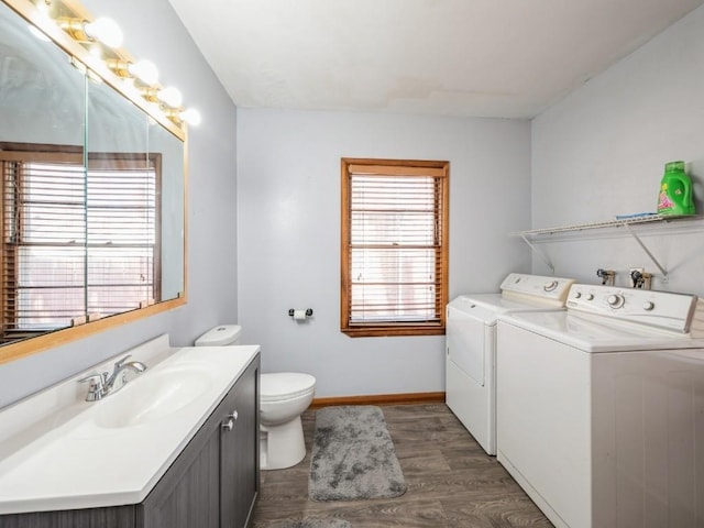 bathroom with toilet, separate washer and dryer, wood finished floors, vanity, and baseboards