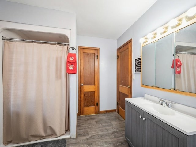 bathroom featuring baseboards, wood finished floors, and vanity