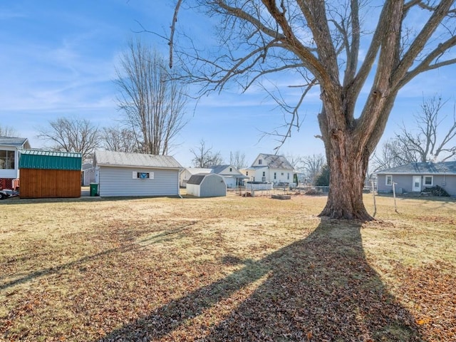 view of yard featuring a residential view, a storage unit, fence, and an outbuilding