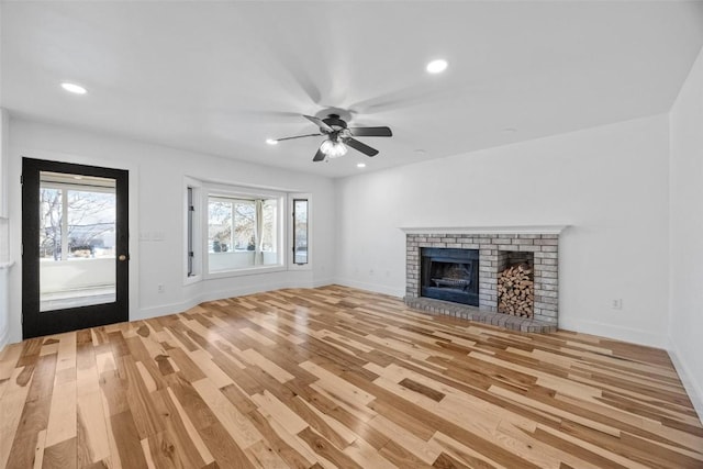 unfurnished living room featuring ceiling fan, a fireplace, and light wood-type flooring