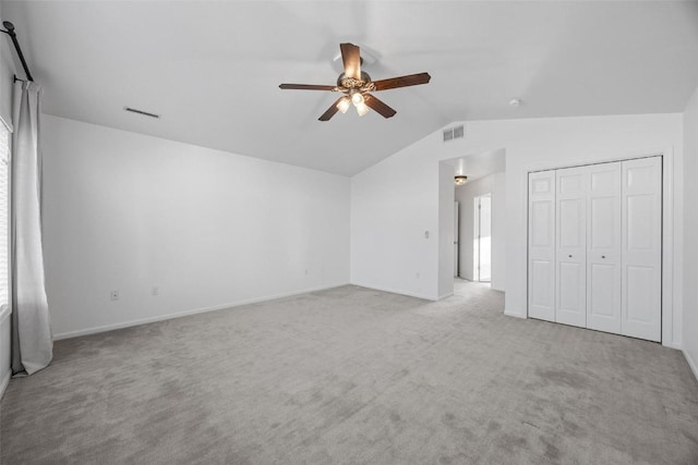 unfurnished bedroom featuring ceiling fan, a closet, light carpet, and vaulted ceiling