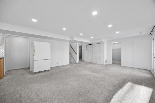 basement with white refrigerator and light carpet