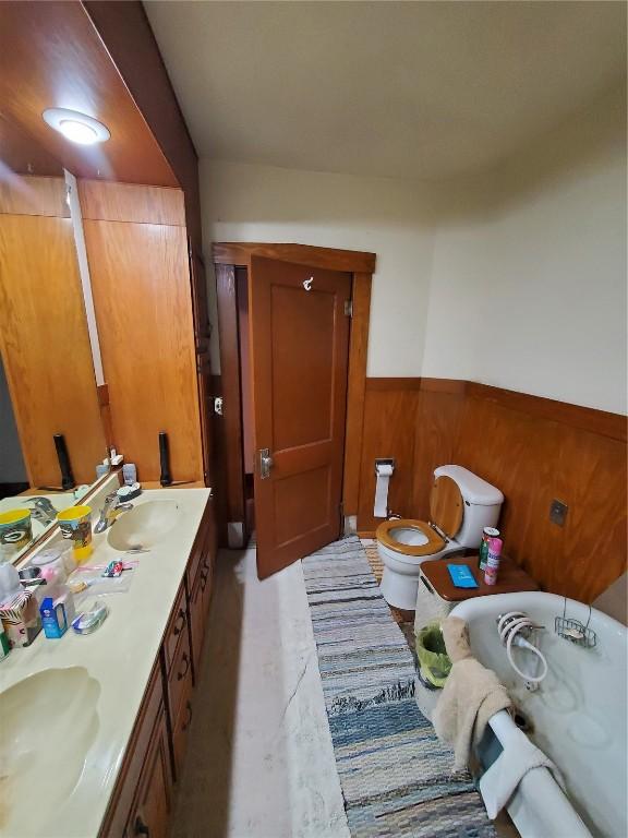 bathroom featuring vanity, toilet, and wood walls