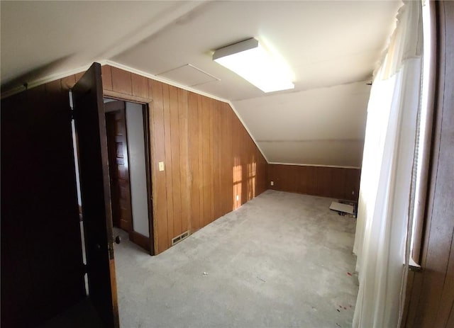 additional living space with light colored carpet, vaulted ceiling, and wooden walls