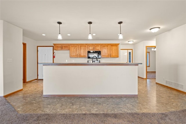 kitchen featuring ceiling fan, sink, a kitchen island, and decorative light fixtures