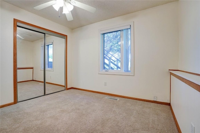 unfurnished bedroom featuring light carpet, a closet, and ceiling fan